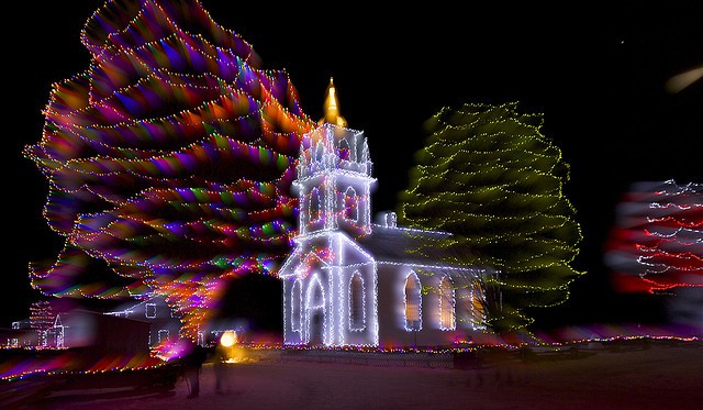 victorian church illuminated by multi-coloured christmas lights. alight at night at upper canada village in morrisburg. 