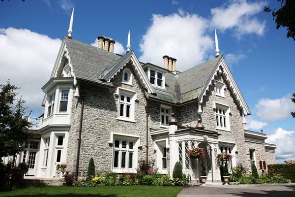 grey stone victorian mansion with gables and white gingerbread trim