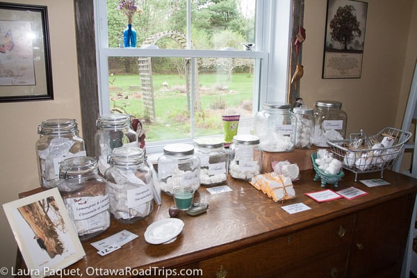 baskets and mason jars filled with soaps and teas, in front of a window looking onto a garden