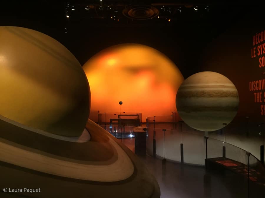 huge models of illuminated planets next to a walkway at the cosmodome in laval, quebec