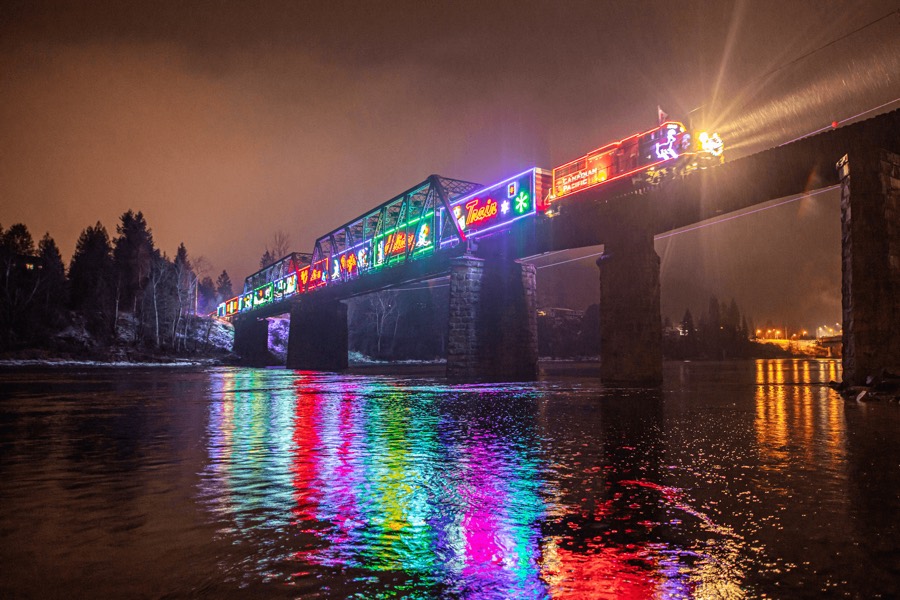 illuminated train crossing an iron bridge at night