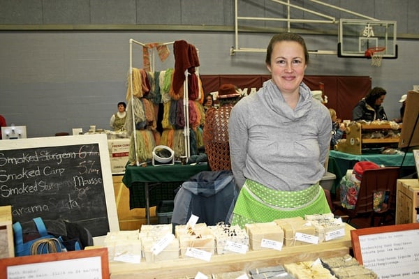 Vendor in grey sweater with a table of cheese.