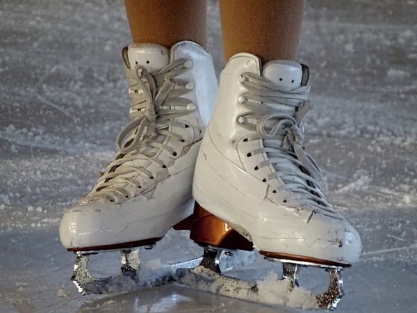 Close-up of a skater's feet with white figure skates (ice skating).