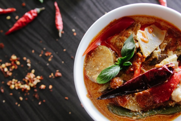 Bowl of soup with chilis on a black table. Photo by Elli O. on Unsplash.