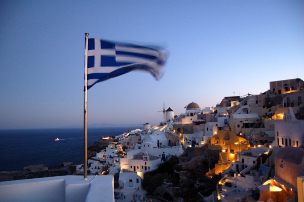 Greek coastline at twilight with Greek flag in foreground.