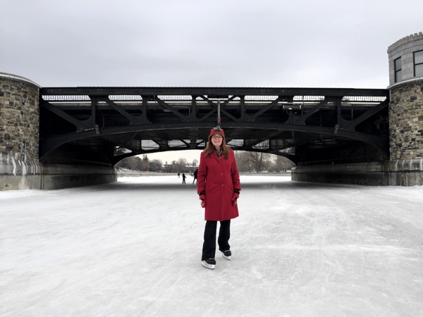 skater in red in front of the pretoria bridge on the rideau canal in ottawa.