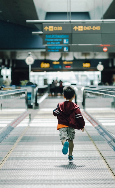 child on moving sidewalk in airport. photo by hanson lu on unsplash.