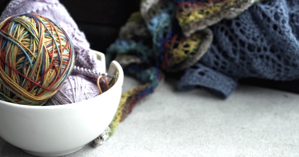 Bowl of yarn with knitting in background.