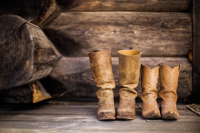 Two pairs of cowboy boots in front of some wood.