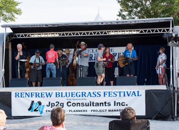 Band on a stage, with spectators, at the Renfrew Bluegrass Festival.