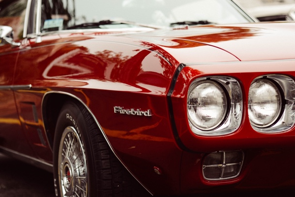 Closeup of the headlight of a classic red Firebird by David Straight.