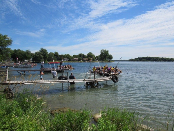 Multiple inner-tube boat teams leaving docks along the St. Lawrence River during the Tubie Race in South Dundas, Ontario.