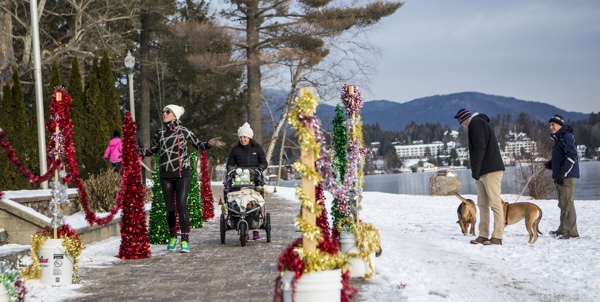 Family with stroller and people walking dogs next to frozen lake in Lake Placid, New York. Photo courtesy of LakePlacid.com.