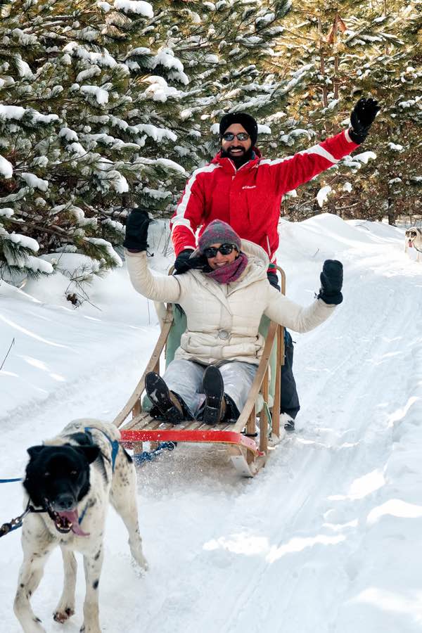 Man in red jacket and woman in white jacket try dogsledding at Timberland Tours Dog Sled Adventures in Bristol, Quebec. Jenn Becker, Hemlock Hills.