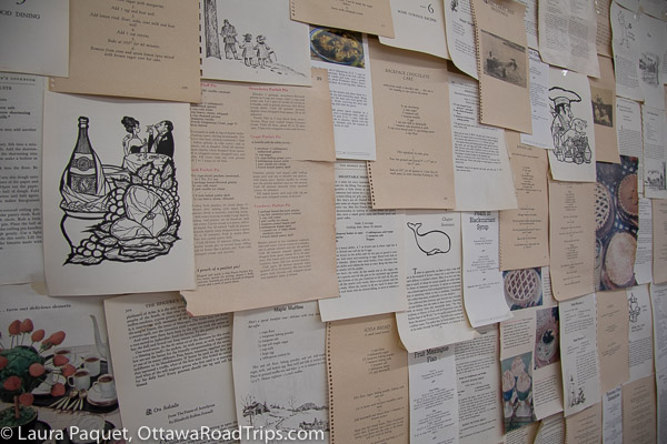 Pages from vintage cookbooks decorate a wall.