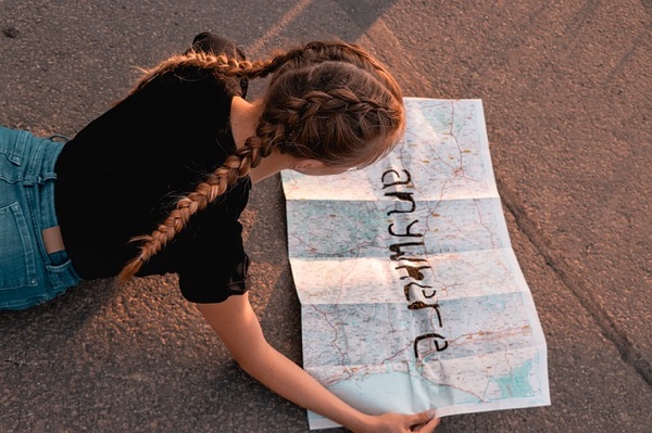 girl planning a road trip with a paper map.