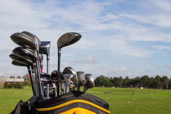 golf clubs in a yellow bag with driving range in background