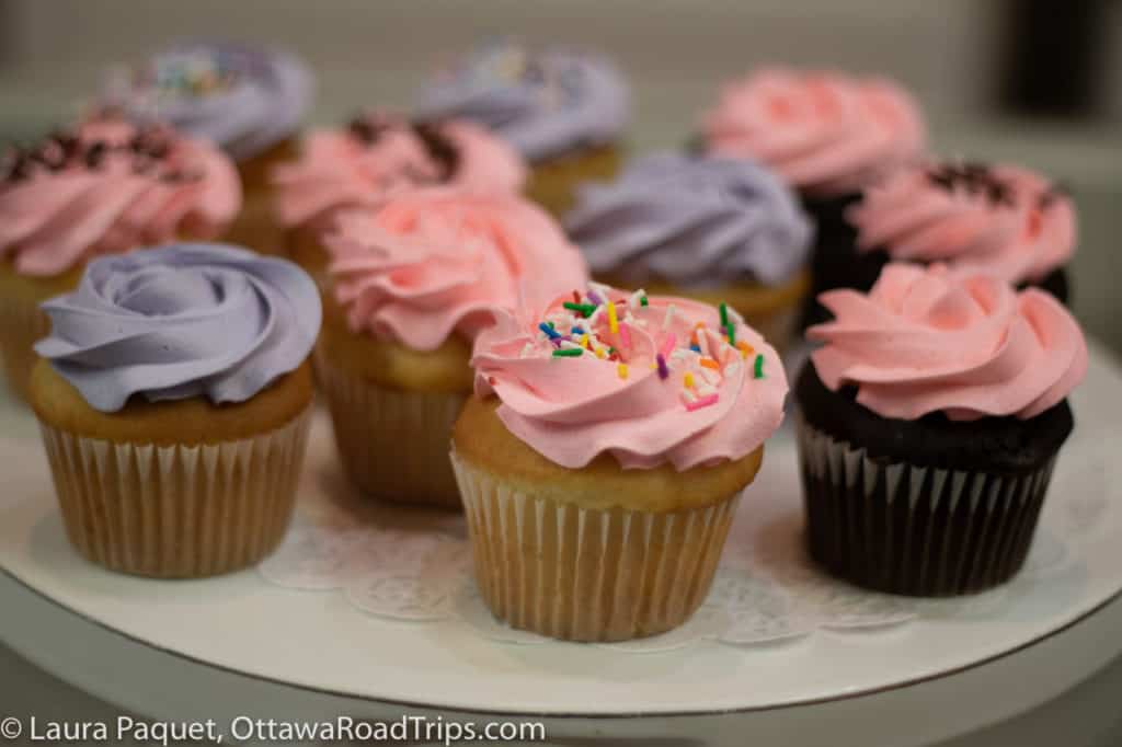 cupcakes with purple or pink frosting and sprinkles, on a white plate
