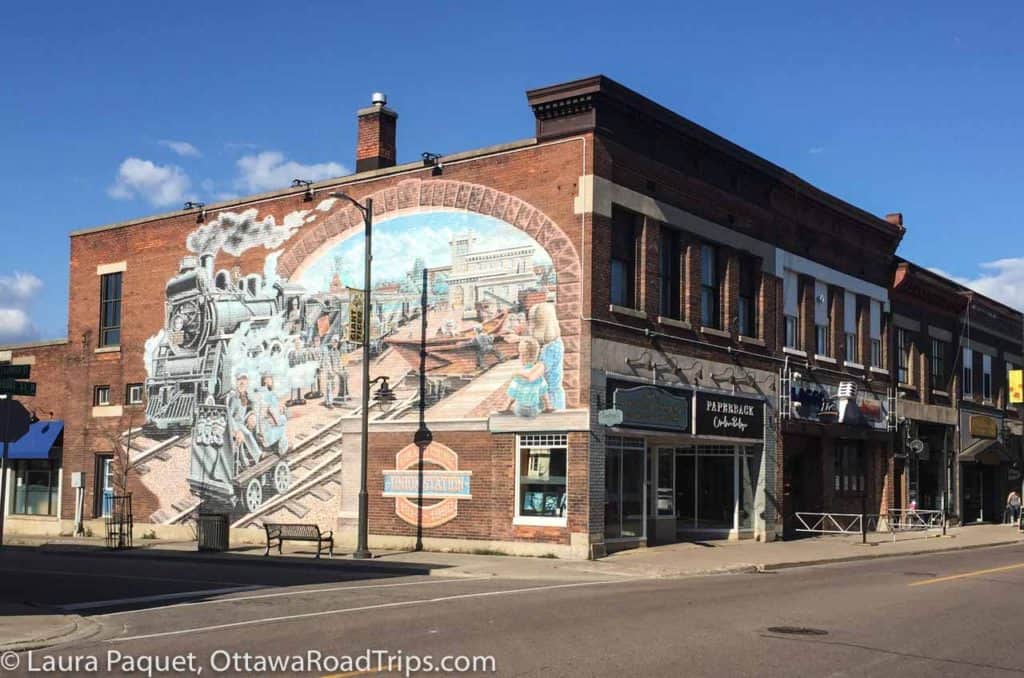 mural on the side of red brick building showing steam locomotive and heritage buildings in pembroke, ontario.