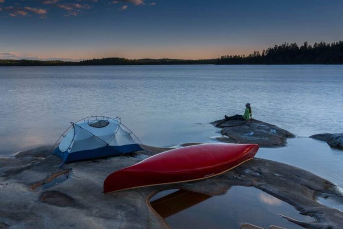 tent and a canoe on a rocky shoreline