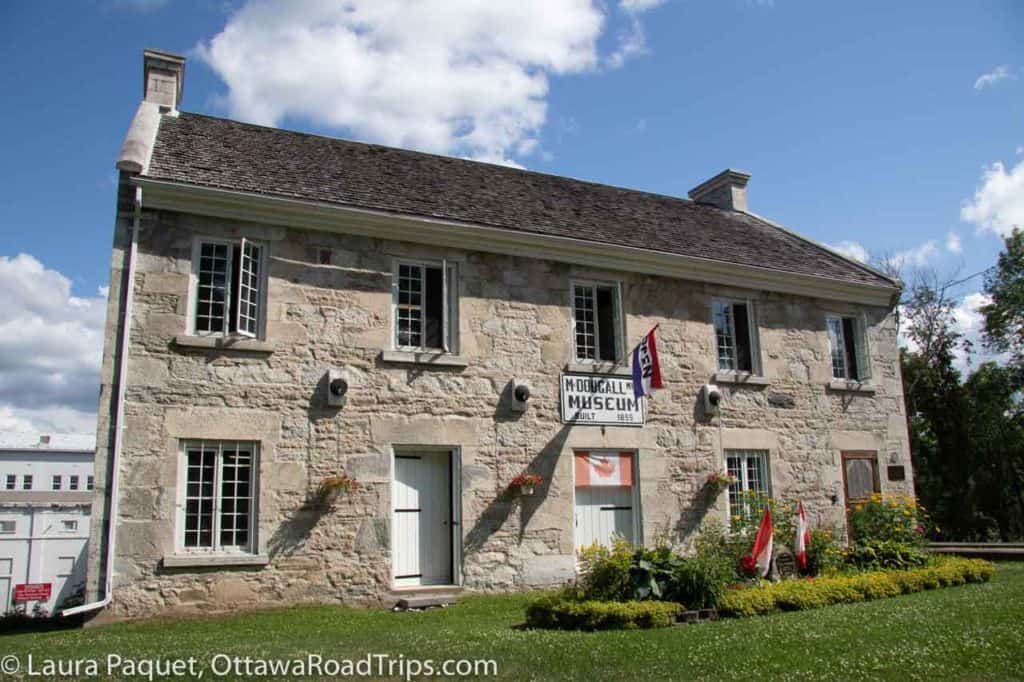 large stone building with mullioned casement windows and flags. the mcdougall mill museum in renfrew, ontario.