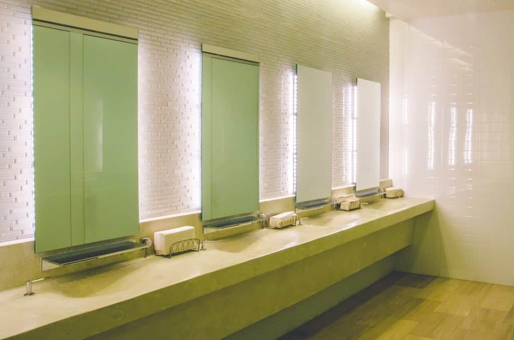 green and white vanity area in a public washroom, with sinks, mirrors and paper hand towels.