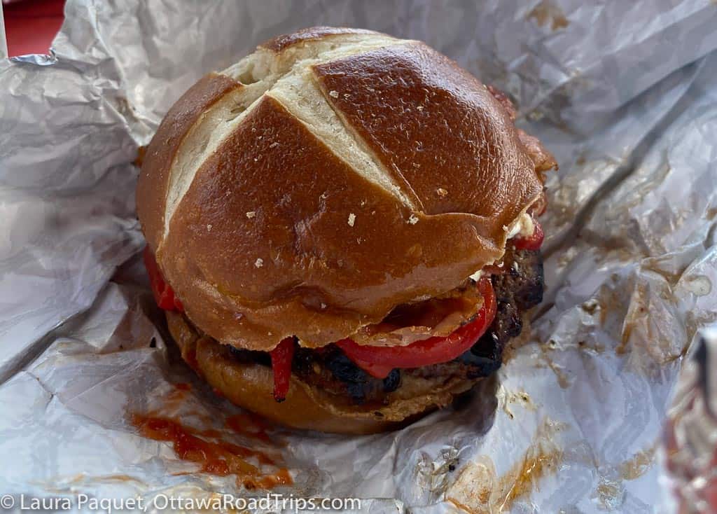 large burger on tin foil wrapping, photographed from above