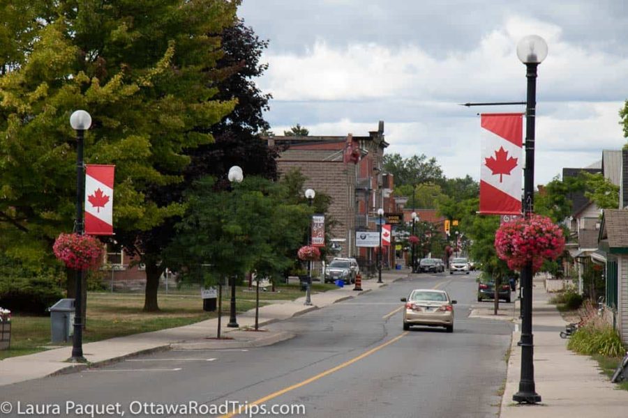 quiet retail street with grey buildings and canadian flag banners