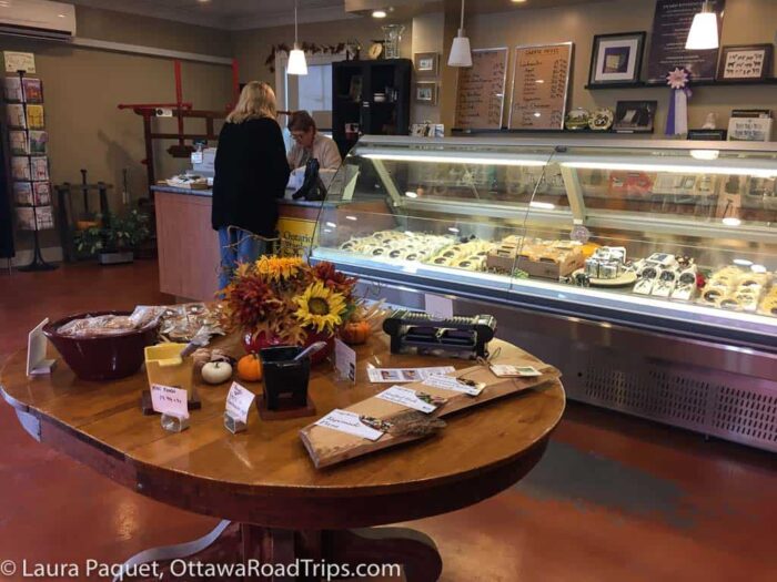 shopper at a cashier next to a large refrigerated cabinet of cheese