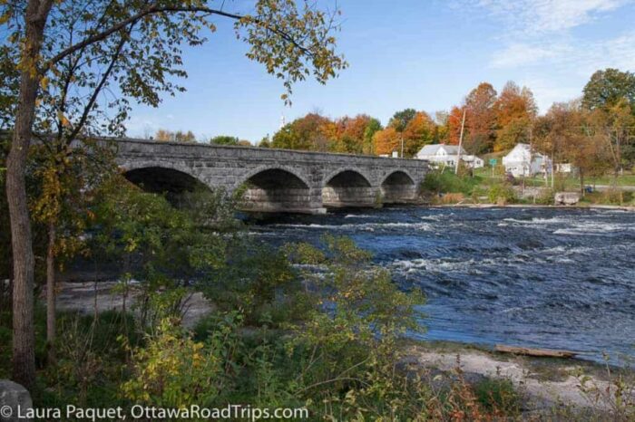 stone bridge across river with five arches, surrounded by fall trees