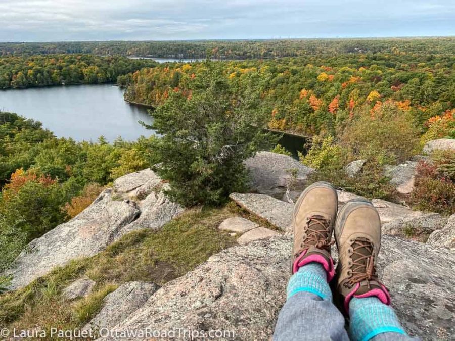 view of river and fall colours with hiking boots at rock dunder in rideau lakes