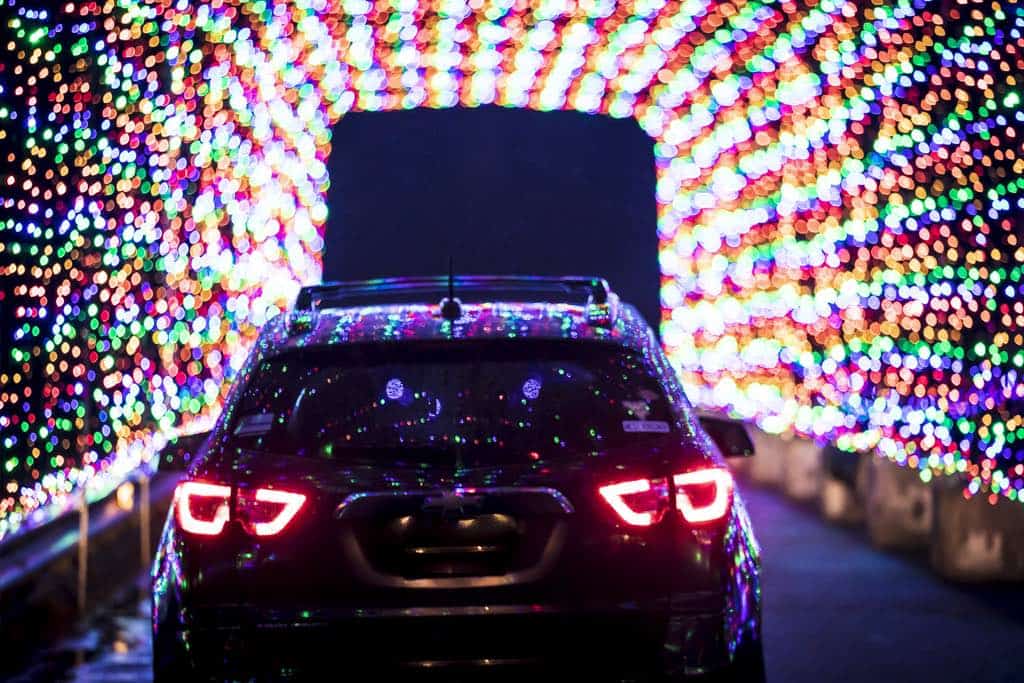 car driving through a tunnel of christmas lights in ottawa at magic of lights.