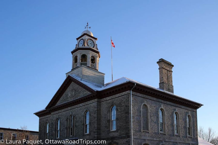 roof of grey limestone building with clock tower and Canadian flag