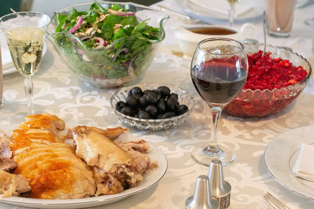 turkey, salad, olives, and glasses of red and white wine on a white damask tablecloth