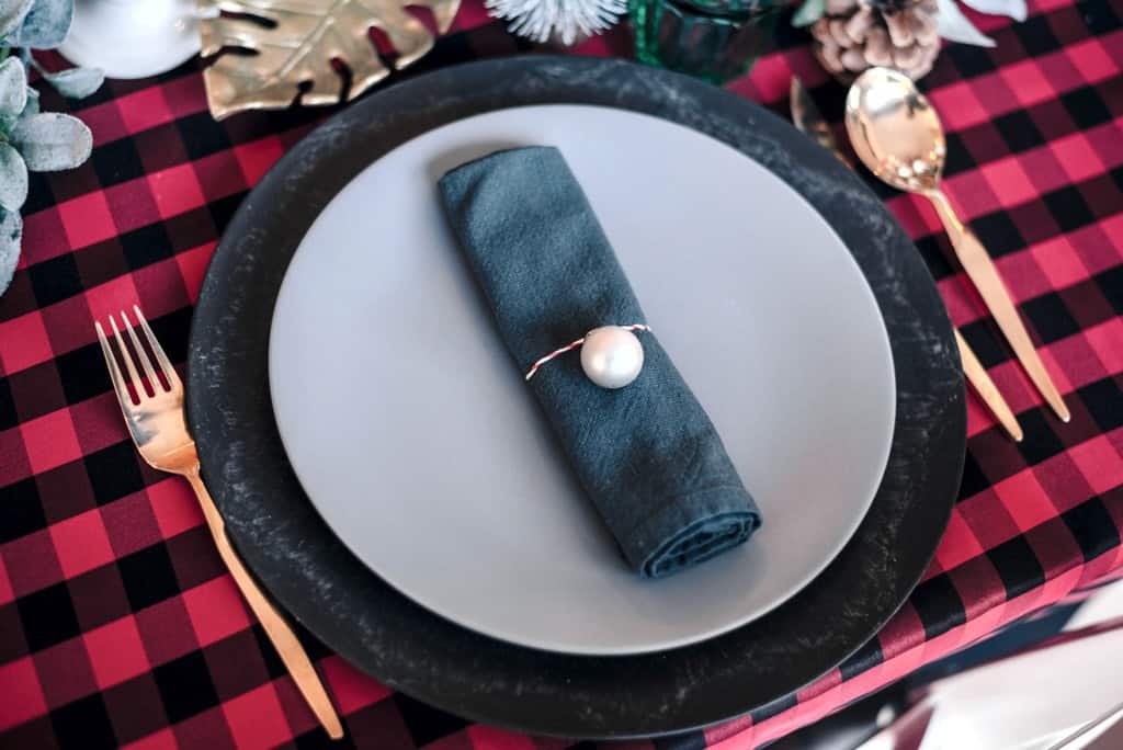 an empty white plate with a blue rim, and a blue cloth napkin, on a red-and-black checked tablecloth