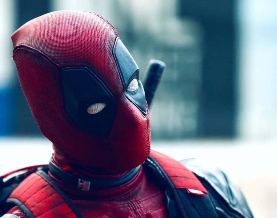 Head and shoulders view of Deadpool superhero character in red and black costume against a blurred background.