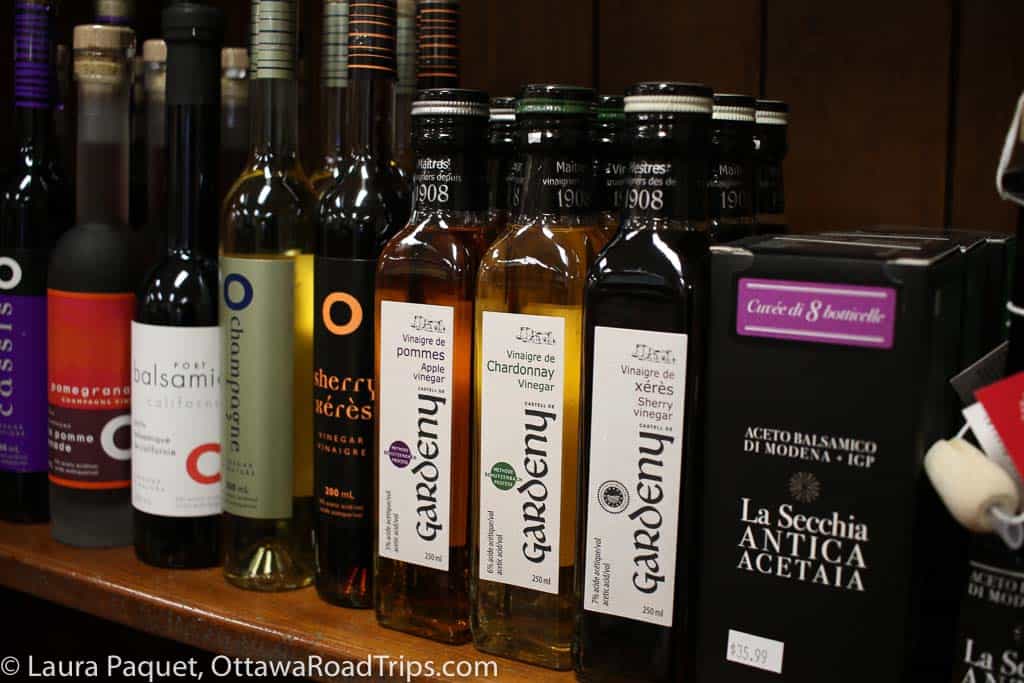 bottles of olive oil and vinegar on a shelf at pêches & poivre, a gourmet food shop.