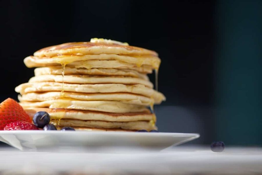 stack of pancakes with maple syrup on a white plate