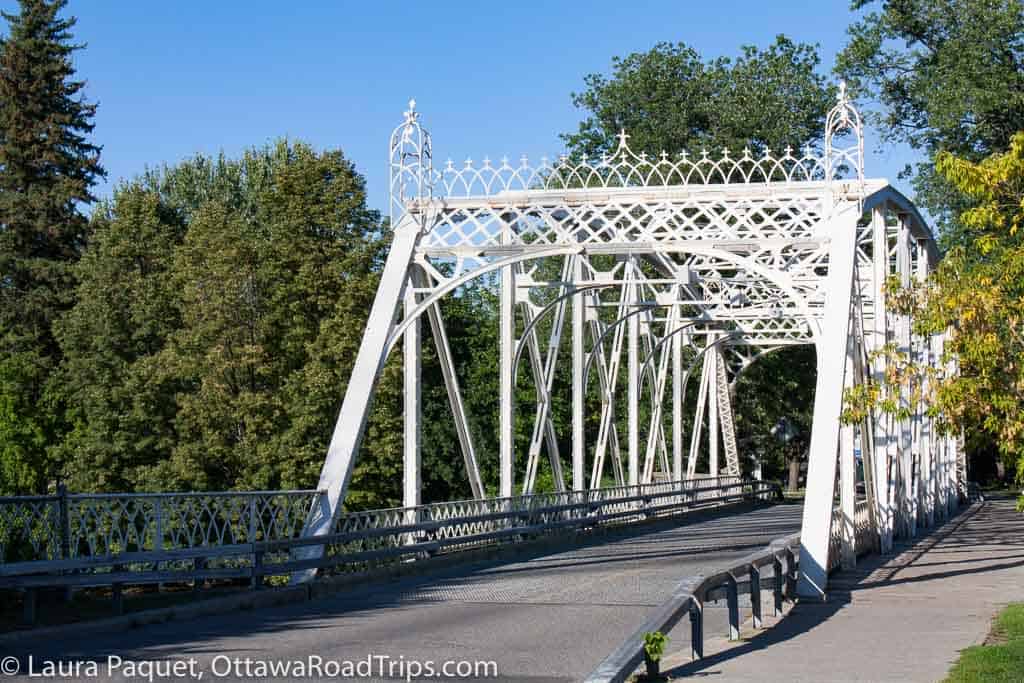 white wrought iron bridge with small road running across it