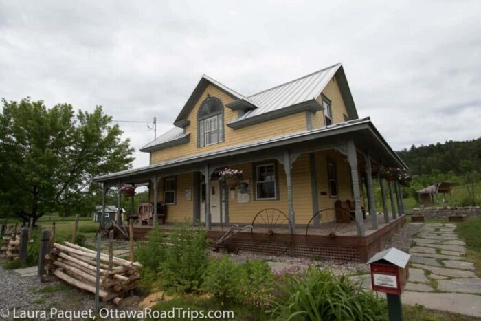 fairbairn house in wakefield, quebec, is housed in a 19th-century farmhouse with yellow siding, tin roof and wraparound porch.