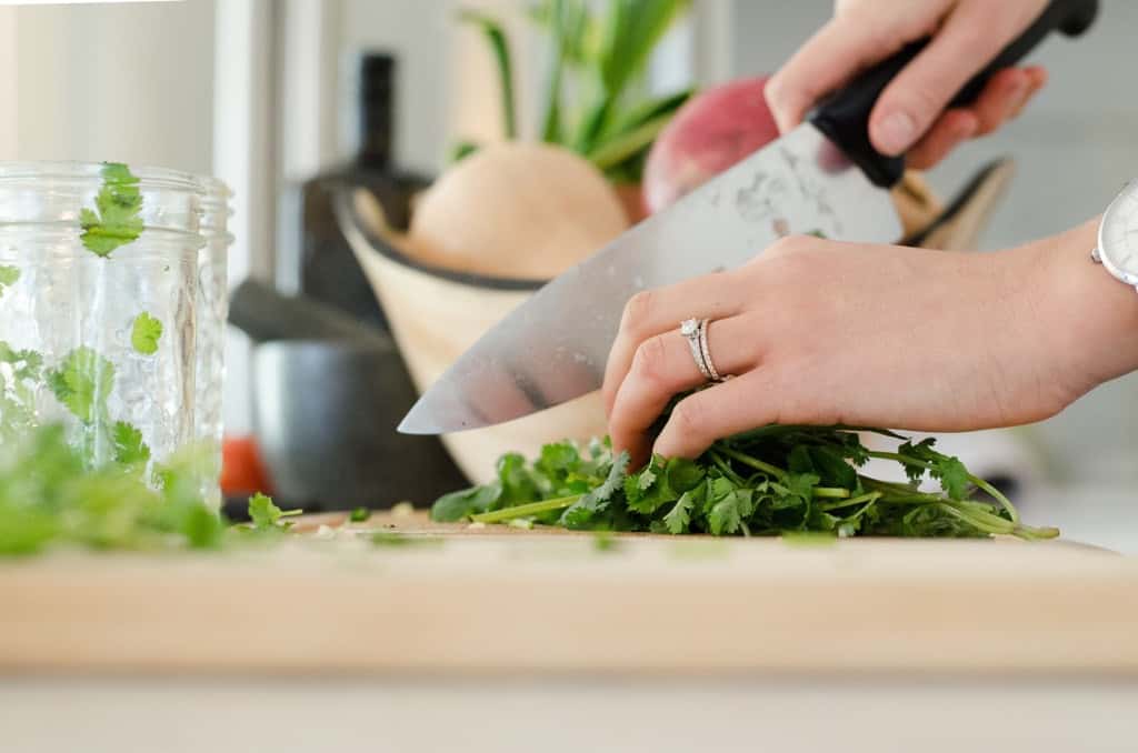 close up of hands on knife chopping cilantro