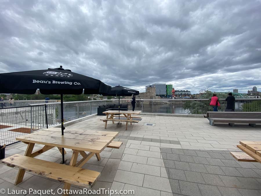 zibi terrasse panorama overlooking ottawa river, with grey skies and beau's beer umbrellas and picnic tables.
