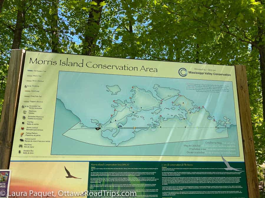 large green and yellow sign at entrance to morris island conservation area, with trail map and historical information.