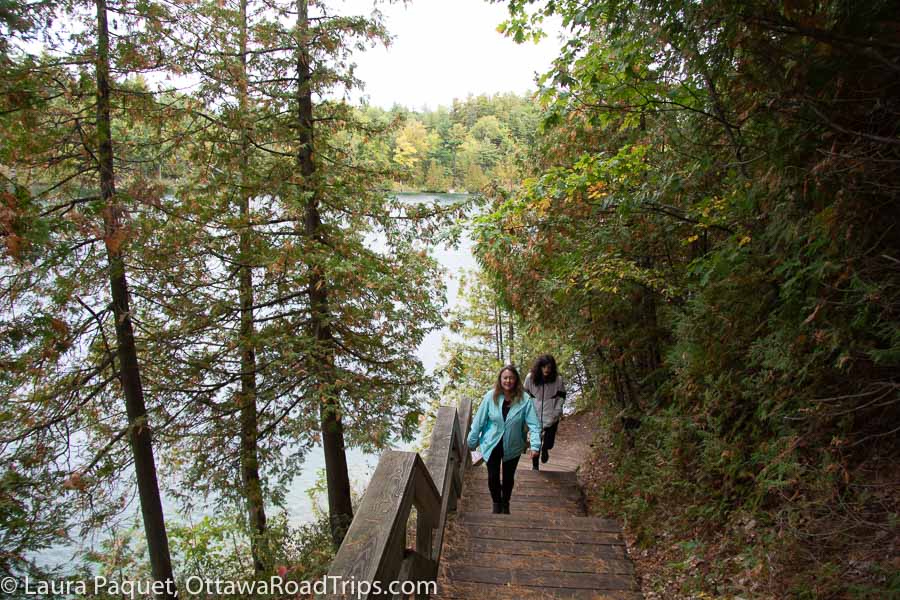 hikers walking down wooden stairs to a small lake