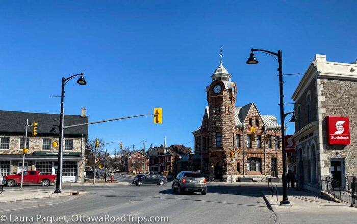 intersection with red sandstone clock tower and limestone shops in arnprior, ontario.