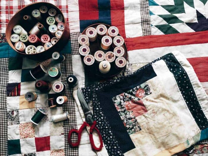 scissors and spools of thread on top of quilt squares