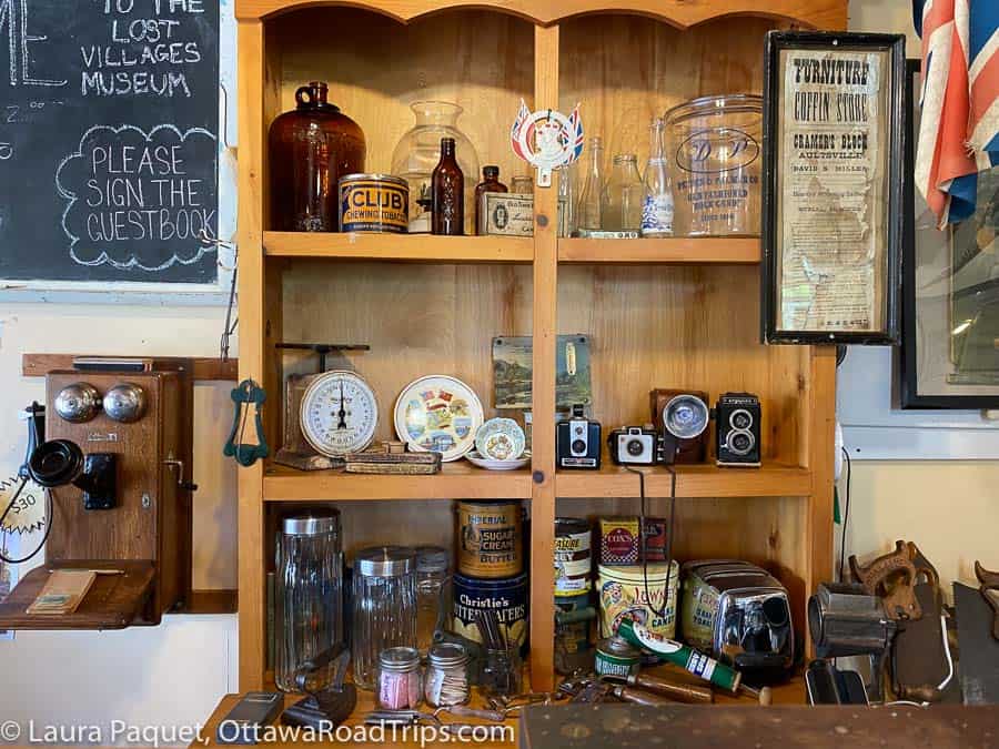 bottles, cameras, jars, tins and other vintage items on wooden shelves at the lost villages museum in long sault, ontario.
