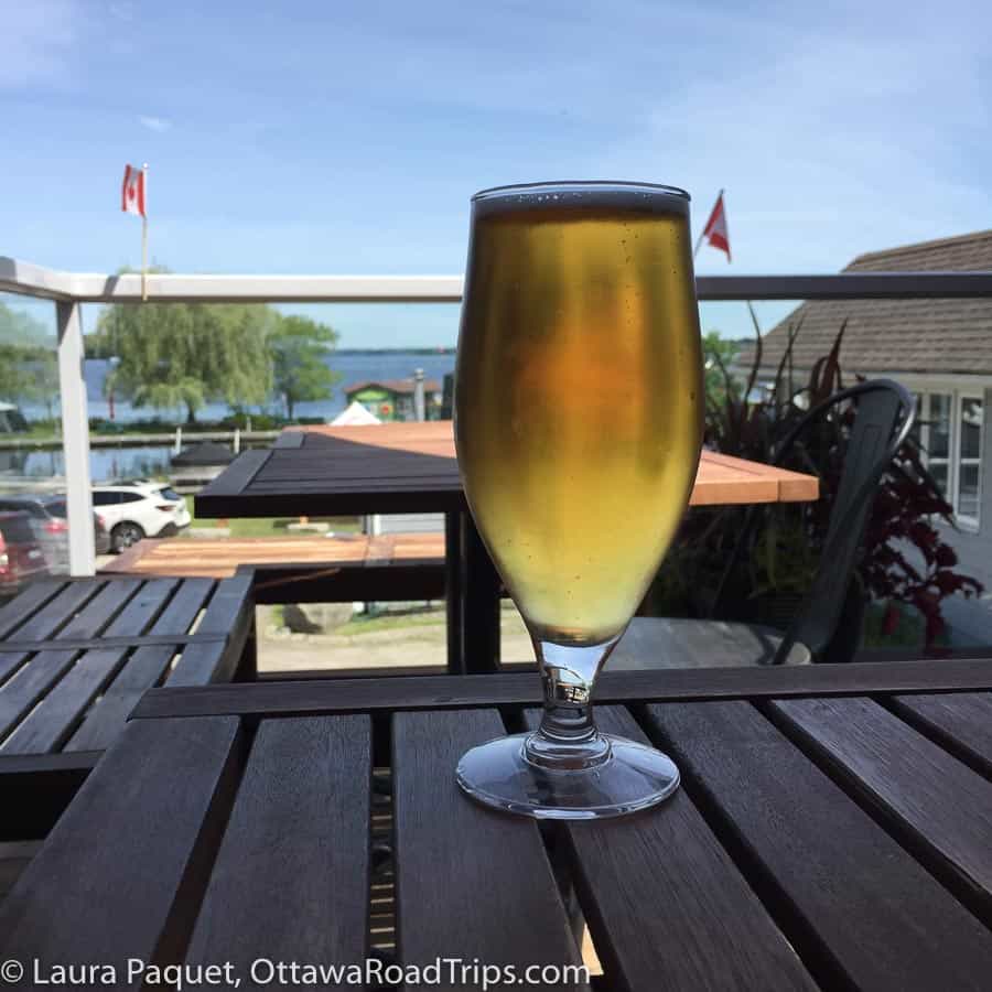 glass of beer on a wooden table overlooking a harbour.