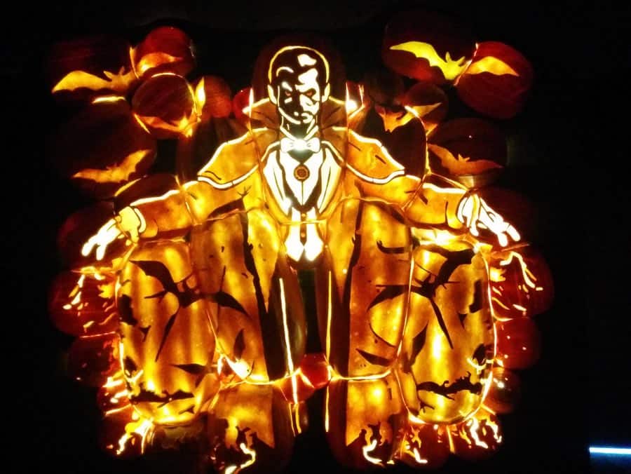 illuminated dracula made out of carved pumpkins against a black background.