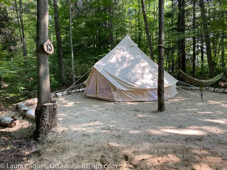 large beige tent or yurt in a clearing in the woods